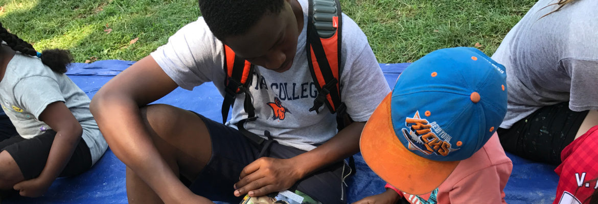 Youth helping a child read a story at G2